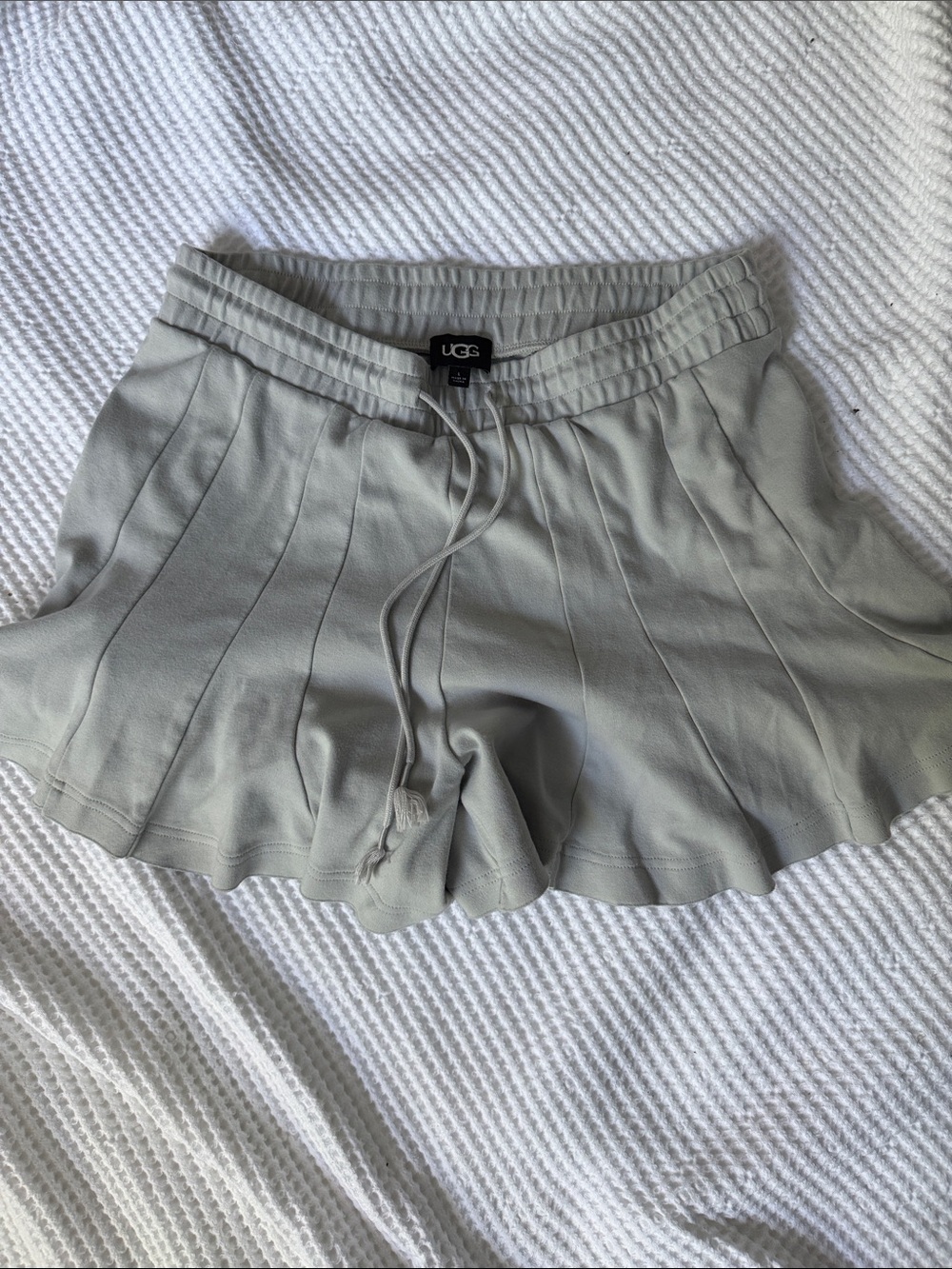 The image displays a light grey UGG paneled lounge short with an elastic drawcor
